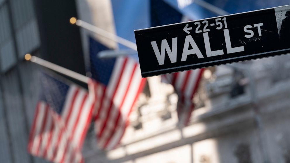 FILE - A sign for Wall Street hangs in front of the New York Stock Exchange, July 8, 2021. Stocks are opening with slight gains on Wall Street Thursday, Dec. 30, keeping the S&P 500 and the Dow Jones Industrial Average hovering just above the latest 