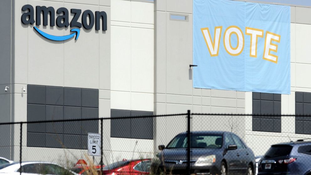 FILE - In this March 30, 2021 file photo, a banner encouraging workers to vote in labor balloting is shown at an Amazon warehouse in Bessemer, Ala. Amazon, under pressure to improve worker rights, has reached a settlement with the National Labor Rela