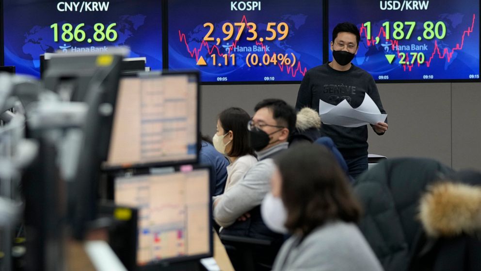 A currency trader walks by screens showing the Korea Composite Stock Price Index (KOSPI) and the foreign exchange rate between U.S. dollar and South Korean won, right, at the foreign exchange dealing room of the KEB Hana Bank headquarters in Seoul, S