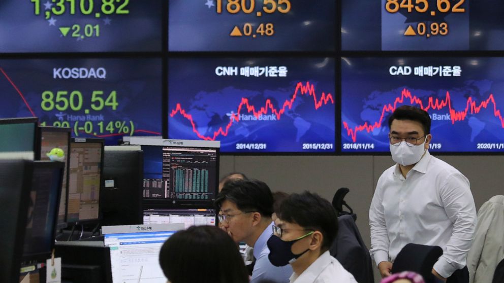 A currency trader passes by screens showing foreign exchange rates at the foreign exchange dealing room of the KEB Hana Bank headquarters in Seoul, South Korea, Thursday, Nov. 19, 2020. Asian stocks followed Wall Street lower on Thursday as anxiety a
