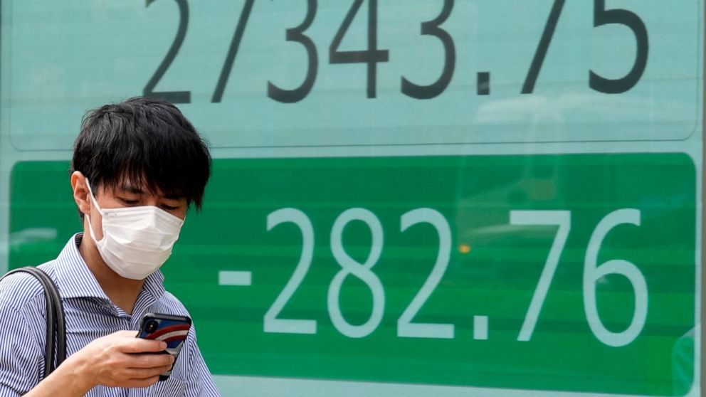 A person wearing a protective mask walks past an electronic stock board showing Japan's Nikkei 225 index at a securities firm Wednesday, Sept. 7, 2022, in Tokyo. Asian shares were mostly lower Wednesday, as pessimism prevailed about higher interest r