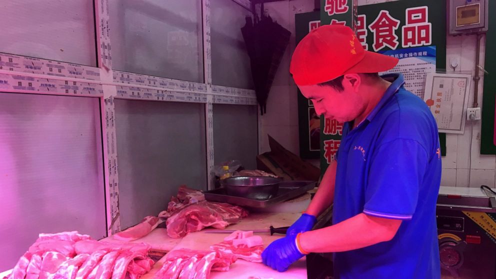 In this Wednesday, Sept. 11, 2019, photo, a butcher slices cuts of pork at a meat market in Beijing. China's government said Wednesday, Sept. 18, 2019, that is releasing pork from official stockpiles to ease a shortage and cool surging prices ahead o