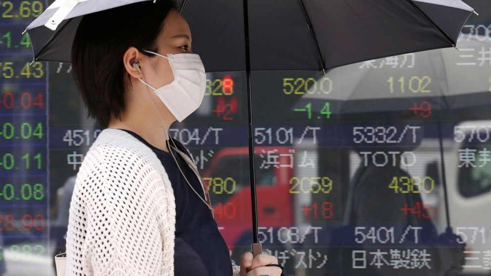 A woman walks by an electronic stock board of a securities firm in Tokyo, Tuesday, July 30, 2019. Shares were mostly higher in Asia on Tuesday as envoys from the U.S. and China prepared to resume trade talks, this time in Shanghai. (AP Photo/Koji Sas