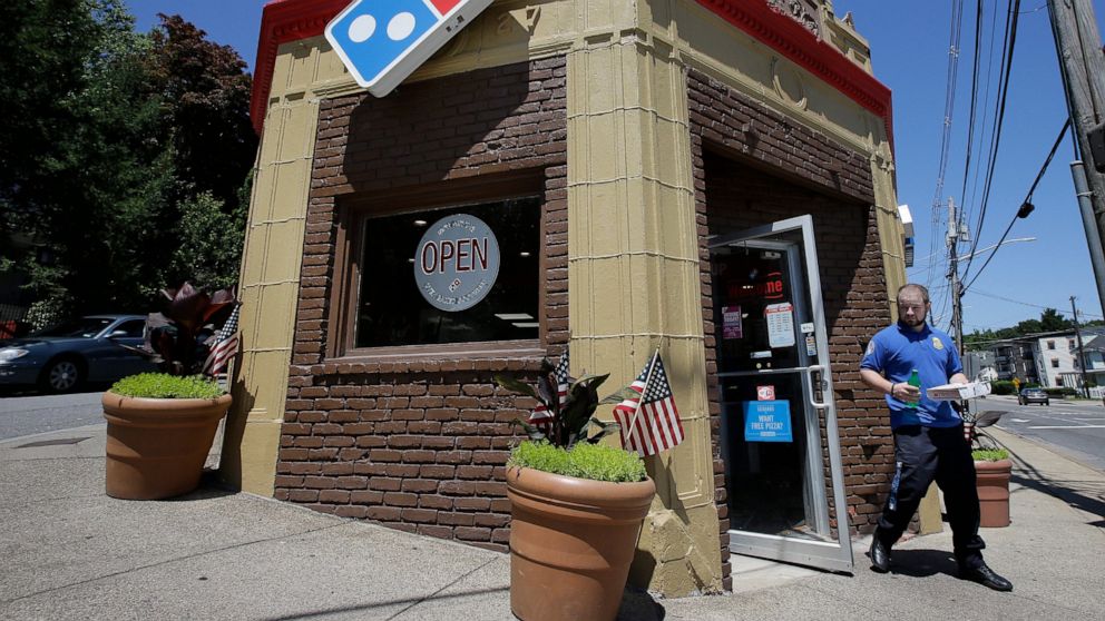 In this Monday, July 15, 2019 photo a customer departs a Domino's location holding food items, in Norwood, Mass. Domino's Pizza Inc. reports earns Tuesday, July 16. (AP Photo/Steven Senne)