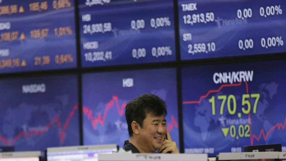 A currency trader smiles at the foreign exchange dealing room of the KEB Hana Bank headquarters in Seoul, South Korea, Friday, Aug. 7, 2020. Asian shares were mostly lower Friday in lackluster trading, as the region weighed continuing trade tensions 