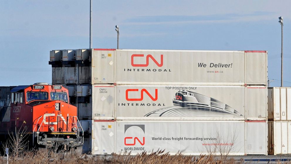 A Canadian National locomotive passes by freight containers at the Canadian National Taschereau yard in Montreal, Saturday, Nov. 28, 2009. Canadian National sweetened its offer to buy Kansas City Southern railroad Thursday, May 13, 2021, and derailed
