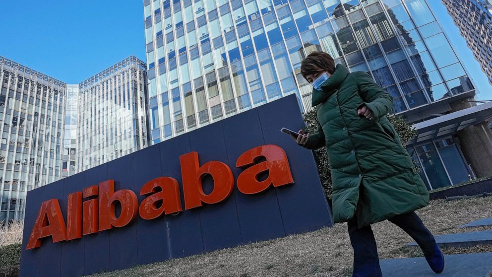 FILE - A woman wearing a face mask run past the offices of Chinese e-commerce firm Alibaba in Beijing on Dec. 13, 2021. Alibaba Group Holding Ltd on Thursday, May 26, 2022, reported a single-digit increase in its fourth-quarter revenue, its slowest q