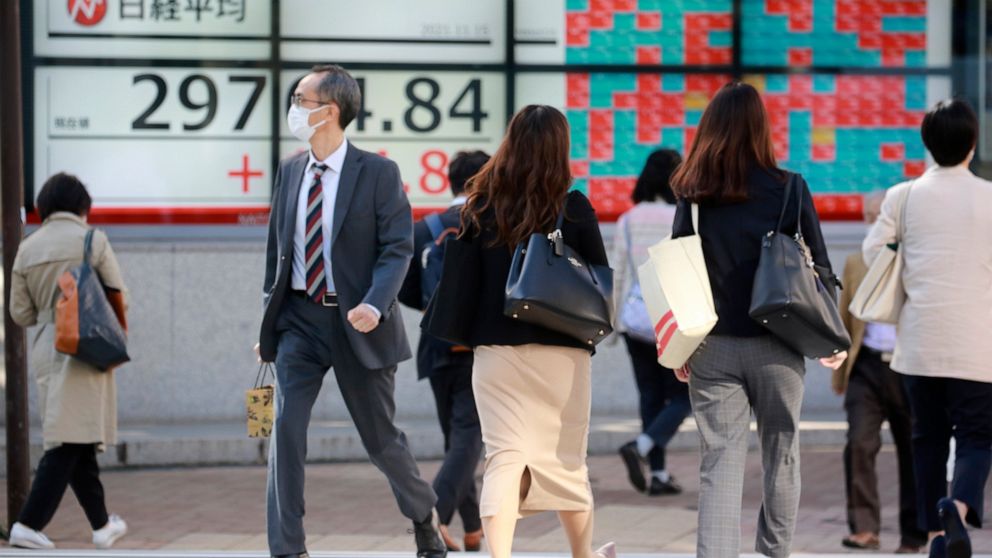 People walk by an electronic stock board of a securities firm in Tokyo, Monday, Nov. 15, 2021. Shares were mixed in Asia on Monday, with the specter of inflation weighing on sentiment.(AP Photo/Koji Sasahara)