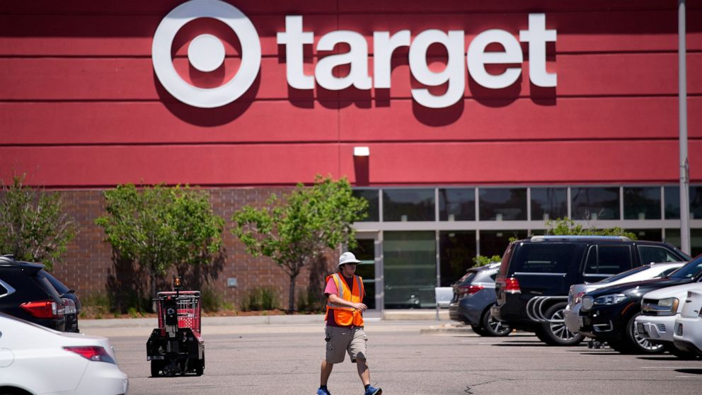 FILE - A worker collects shopping carts in the parking lot of a Target store on Wednesday, June 9, 2021, in Highlands Ranch, Colo. Target reported solid sales for the fiscal second quarter of 2022, but its profits plunged nearly 90% because it slashe