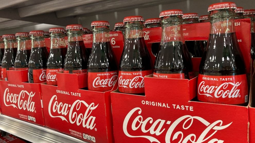 Bottles of Coca-Cola are stacked on a shelf in a grocery store, Wednesday, Dec. 15, 2021, in Surfside, Fla. Coca-Cola’s revenue rose 10% to $9.5 billion in the fourth quarter, Thursday, Feb. 10, 2022, as coffee shops, movie theaters and other venues 