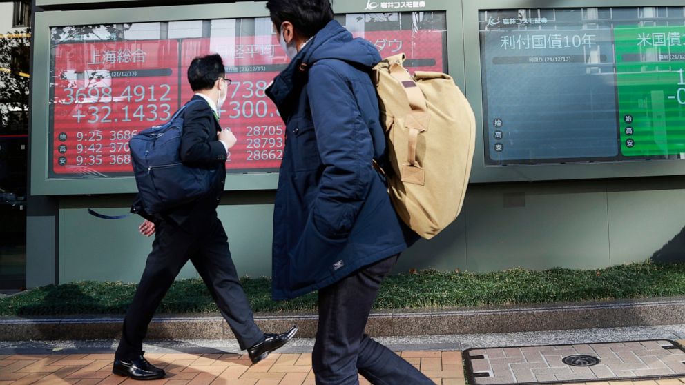 People walk by an electronic stock board of a securities firm in Tokyo, Monday, Dec. 13, 2021. (AP Photo/Koji Sasahara)