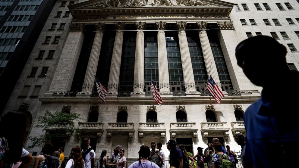 FILE - Pedestrians walk past the New York Stock Exchange on Friday, July 8, 2022, in New York. Stocks wavered between gains and losses in morning trading on Wall Street Monday, Aug. 1, 2022 as investors face another busy week of corporate earnings re
