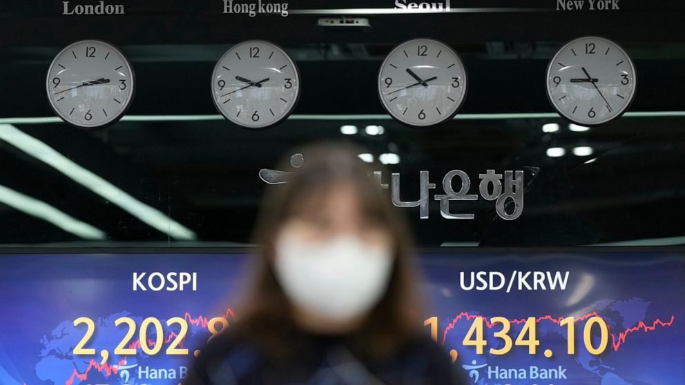 A currency trader walks by the screens showing the Korea Composite Stock Price Index (KOSPI), left, and the foreign exchange rate between U.S. dollar and South Korean won at a foreign exchange dealing room in Seoul, South Korea, Tuesday, Oct. 4, 2022