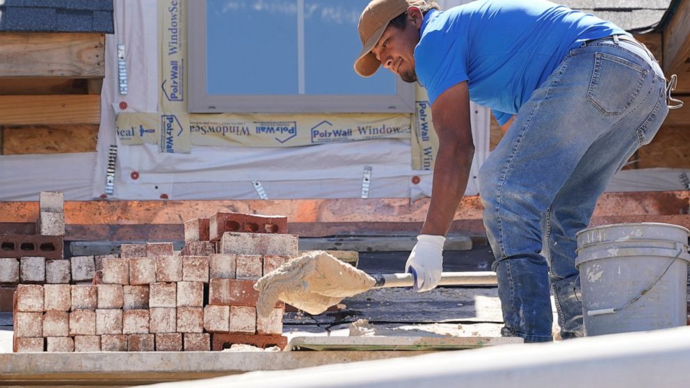 FILE - A mason shovels a cement mixture as he prepares to lay down bricks on the exterior wall of a new house in Flowood, Miss., Sept. 23, 2021. U.S. home construction fell 1.6% in September as builders continue to be tripped up by supply chain bottl
