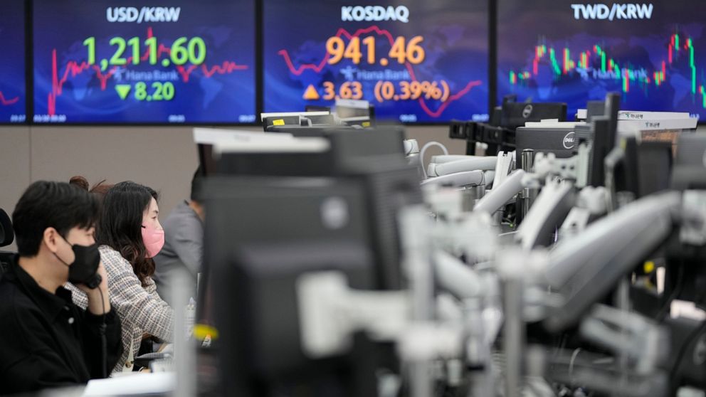 Currency traders watch computer monitors near screen showing the foreign exchange rate between U.S. dollar and South Korean won, left, at a foreign exchange dealing room in Seoul, South Korea, Wednesday, March 30, 2022. Asian stock markets followed W