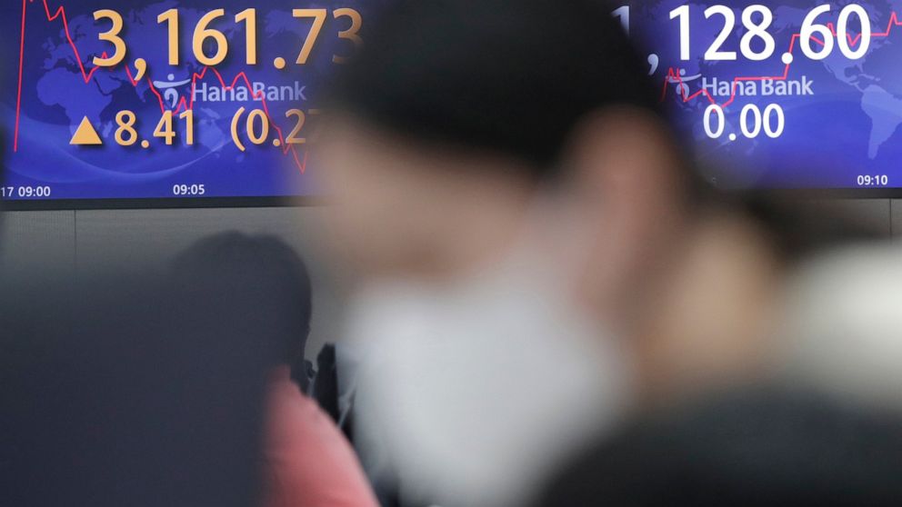 A currency trader watches computer monitors near screens showing the Korea Composite Stock Price Index (KOSPI), left, and the foreign exchange rate between U.S. dollar and South Korean won at a bank's foreign exchange dealing room in Seoul, South Kor