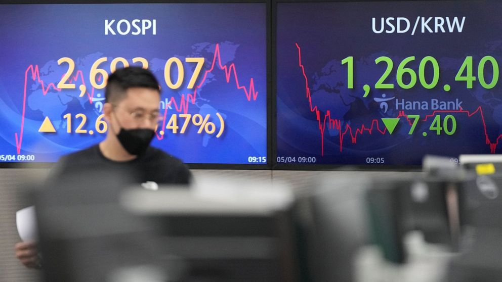 A currency trader walks by the screens showing the Korea Composite Stock Price Index (KOSPI), left, and the foreign exchange rate between U.S. dollar and South Korean won at a foreign exchange dealing room in Seoul, South Korea, Wednesday, May 4, 202