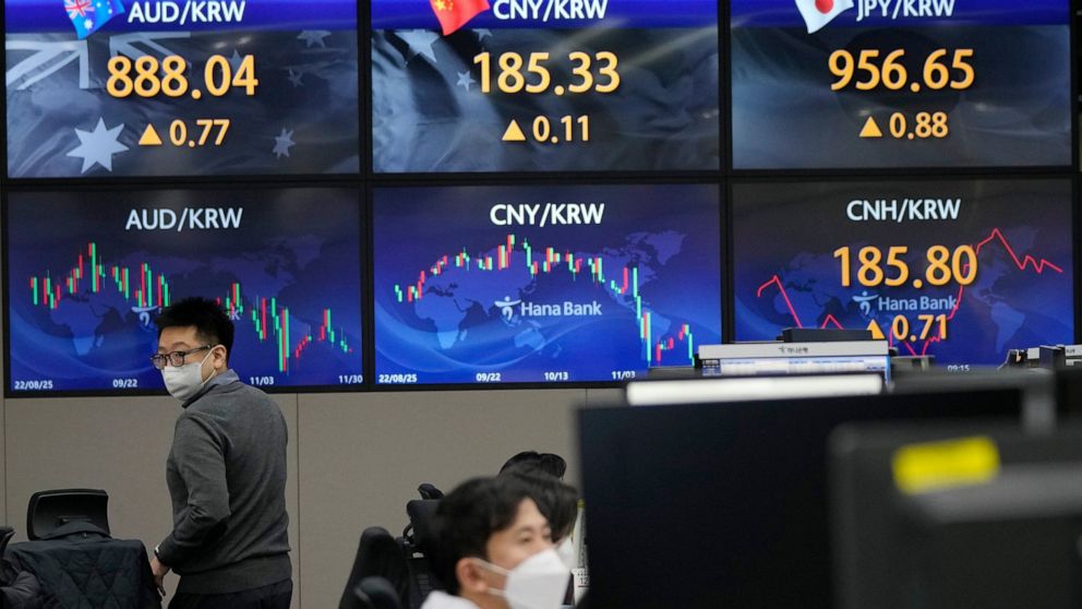 A currency trader passes by the screens showing the foreign exchange rates at the foreign exchange dealing room of the KEB Hana Bank headquarters in Seoul, South Korea, Wednesday, Nov. 30, 2022. Asian shares were mostly lower Wednesday ahead of a clo