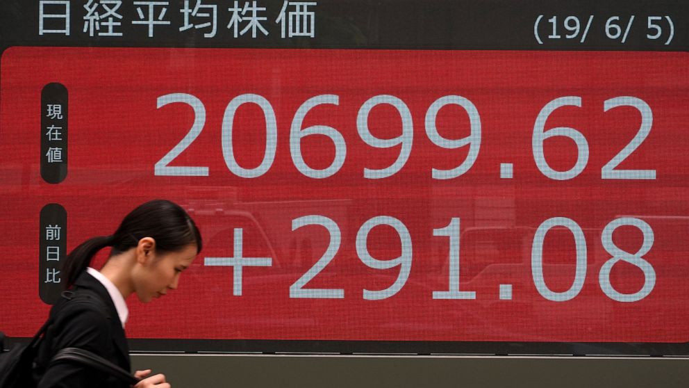 A woman walks past an electronic stock board showing Japan's Nikkei 225 index at a securities firm in Tokyo Wednesday, June 5, 2019. Shares surged Wednesday in Asia following a rally on Wall Street spurred by signs the Federal Reserve is ready to cut