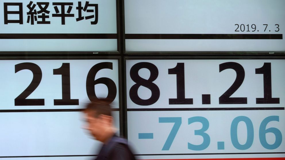A man walks past an electronic stock board showing Japan's Nikkei 225 index at a securities firm in Tokyo Wednesday, July 3, 2019. Shares fell back in Asia on Wednesday as the euphoria from President Donald Trump’s truce with China’s Xi Jinping on tr