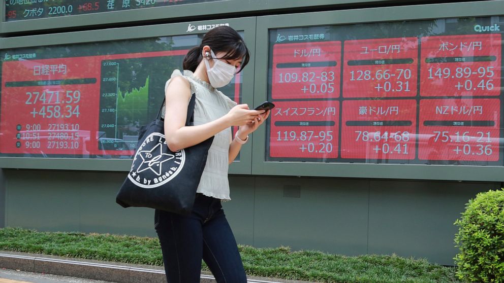 A woman walks by an electronic stock board of a securities firm in Tokyo, Monday, Aug. 23, 2021. Asian shares rose Monday as investor sentiment received a big boost from the rally last week on Wall Street, despite worries about the more contagious co