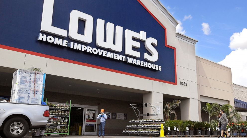 FILE- In this March 22, 2020 file photo customers wearing masks walk into a Lowe's home improvement store in the Canoga Park section of Los Angeles. A massive surge in online sales and increased business at its U.S. stores helped push Lowe’s second-q