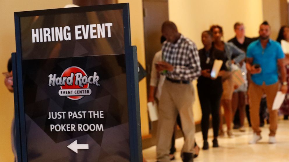FILE - In this June 4, 2019 file photo, job applicants line up at the Seminole Hard Rock Hotel & Casino Hollywood during a job fair in Hollywood, Fla. The number of open U.S. jobs slipped 0.4% in July, while hires rose slightly, a sign that some empl