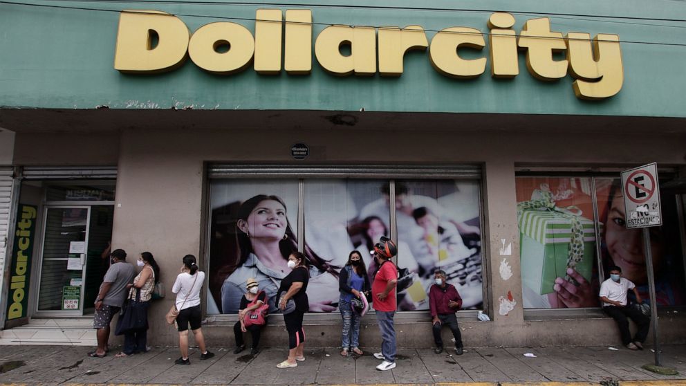 Shoppers, wearing protective face masks, form a line outside Dollarcity in San Salvador, El Salvador, Thursday, Aug. 6, 2020, amid the new coronavirus pandemic. For months, the strictest measures confronting the COVID-19 pandemic in Latin America see