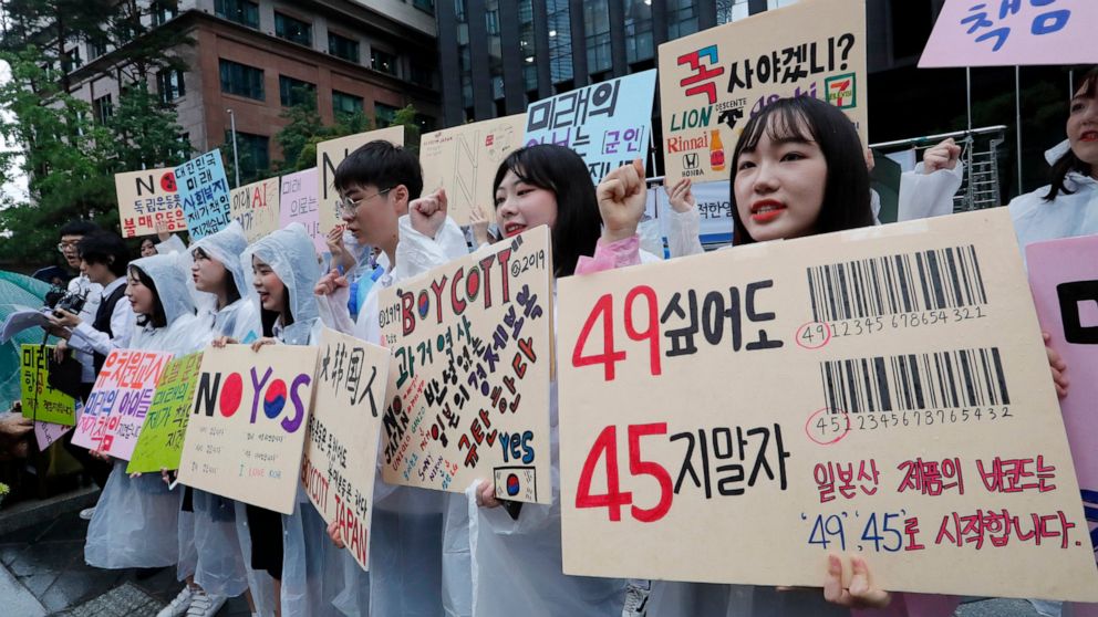 South Korean high school students shout slangs during a rally denouncing the Japanese government's decision on their exports to South Korea in front of the Japanese embassy in Seoul, South Korea, Friday, July 26, 2019. The signs read: "We denounce Ja