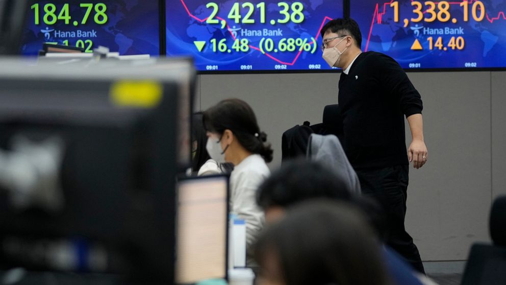 A currency trader passes by screens showing the Korea Composite Stock Price Index (KOSPI), center, and the exchange rate of South Korean won against the U.S. dollar, right, at the foreign exchange dealing room of the KEB Hana Bank headquarters in Seo
