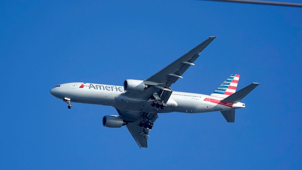 An American Airlines Boeing 777 is framed by utility wires as it prepares to land at Miami International Airport, Wednesday, Jan. 27, 2021, in Miami. The airline said Thursday that it lost $2.2 billion in the fourth quarter, with revenue plunging by 