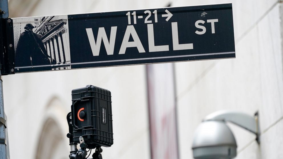 FILE - A Wall Street sign is seen next to surveillance equipment outside the New York Stock Exchange, Oct. 5, 2021, in New York. Stocks are falling in early trading Monday, Dec. 20, 2021 continuing a weak stretch as traders keep a wary eye on global 