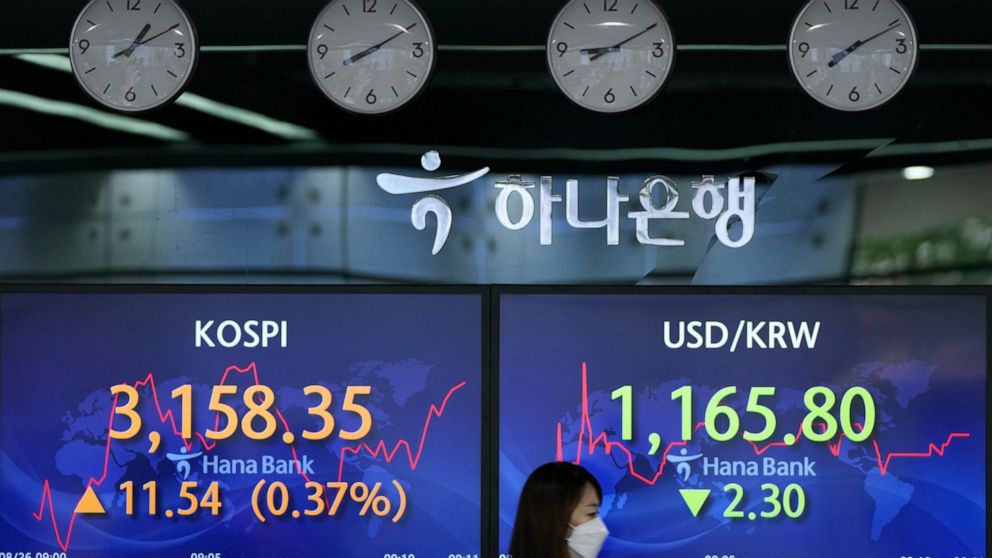 A currency trader walks by screens showing the Korea Composite Stock Price Index (KOSPI), left, and the foreign exchange rate between U.S. dollar and South Korean won at a foreign exchange dealing room in Seoul, South Korea, Thursday, Aug. 26, 2021. 