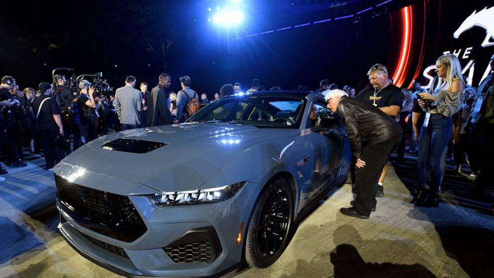 Visitors look over one of the models of the 2024 Ford Mustang at the North American International Auto Show, Wednesday, Sept. 14, 2022, in Detroit. (AP Photo/Jose Juarez)