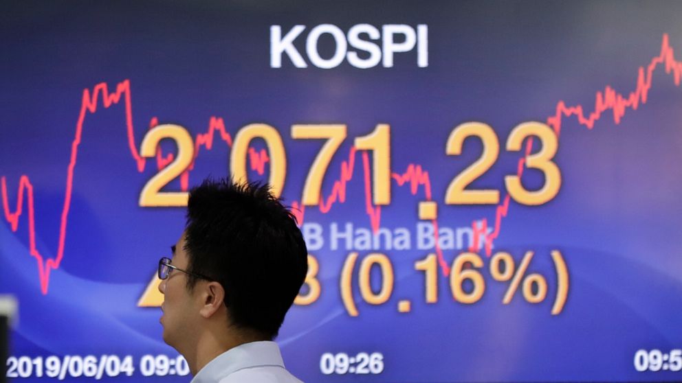 A currency trader walks by the screen showing the Korea Composite Stock Price Index (KOSPI) at the foreign exchange dealing room in Seoul, South Korea, Tuesday, June 4, 2019. Shares are mixed in Asia after a tumultuous session for tech shares on Wall