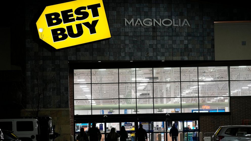 FILE - Shoppers are silhouetted as they walk toward a Best Buy store after doors opened at 5 a.m., Nov. 26, 2021, in Lone Tree, Colo. Best Buy Co. posted first-quarter results that showed shoppers pulled back on their spending and higher costs ate in