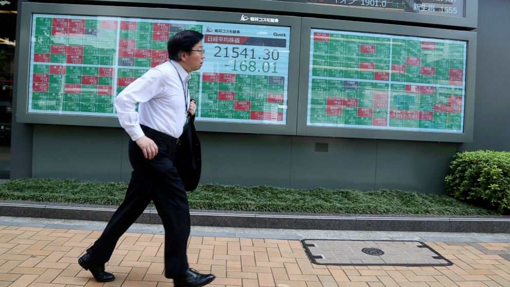A man pases by an electronic stock board of a securities firm in Tokyo, Wednesday, July 31, 2019. Asian shares were mostly lower Wednesday as investors looked cautiously ahead to a key policy update from the U.S. Federal Reserve later in the day. (AP