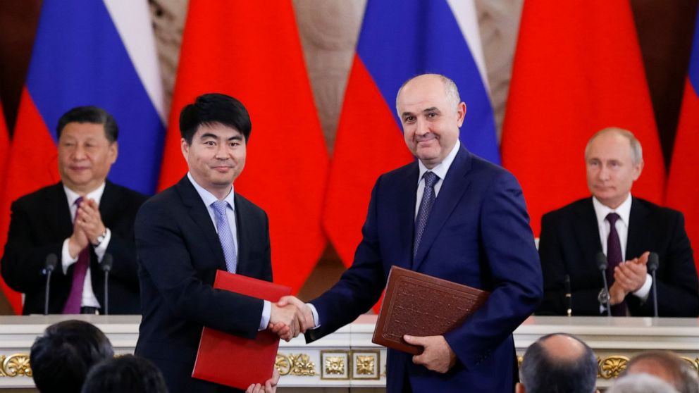 Guo Ping, deputy Chairman of Huawei Technologies Co Ltd, foreground left, shakes hands with Russian President of MTS mobile network operator, Alexei Kornya as Russian President Vladimir Putin, right, and Chinese President Xi Jinping attend a signing 