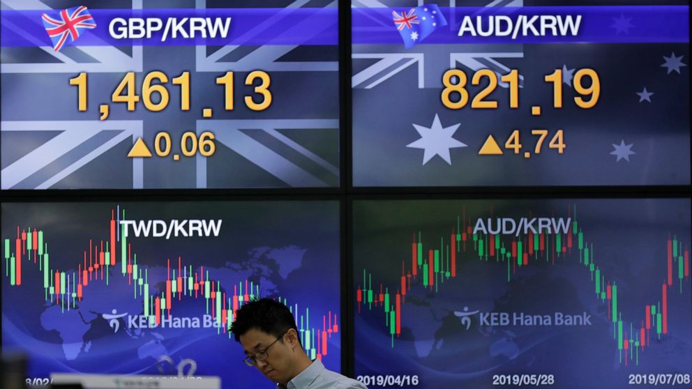 A currency trader walks by the screens showing the foreign exchange rates at the foreign exchange dealing room in Seoul, South Korea, Monday, July 8, 2019. Asian stocks tumbled Monday after relatively strong U.S. employment data tempered hopes the Fe