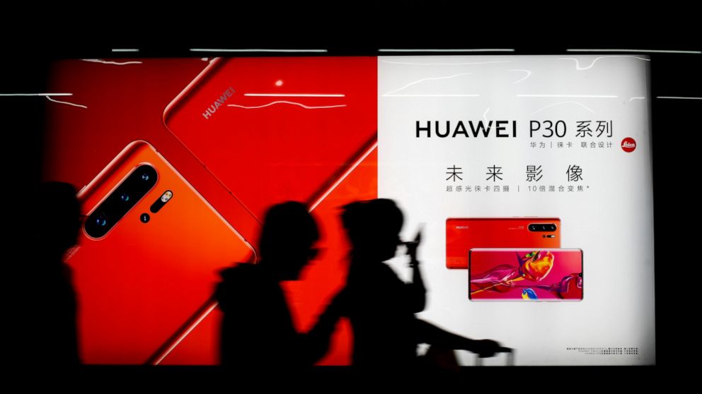 FILE - In this May 13, 2019, file photo, commuters walk by the new Huawei P30 smartphone advertisement on display inside a subway station in Beijing. Two months after U.S.-Chinese talks aimed at ending a tariff war broke down, both sides are trying t