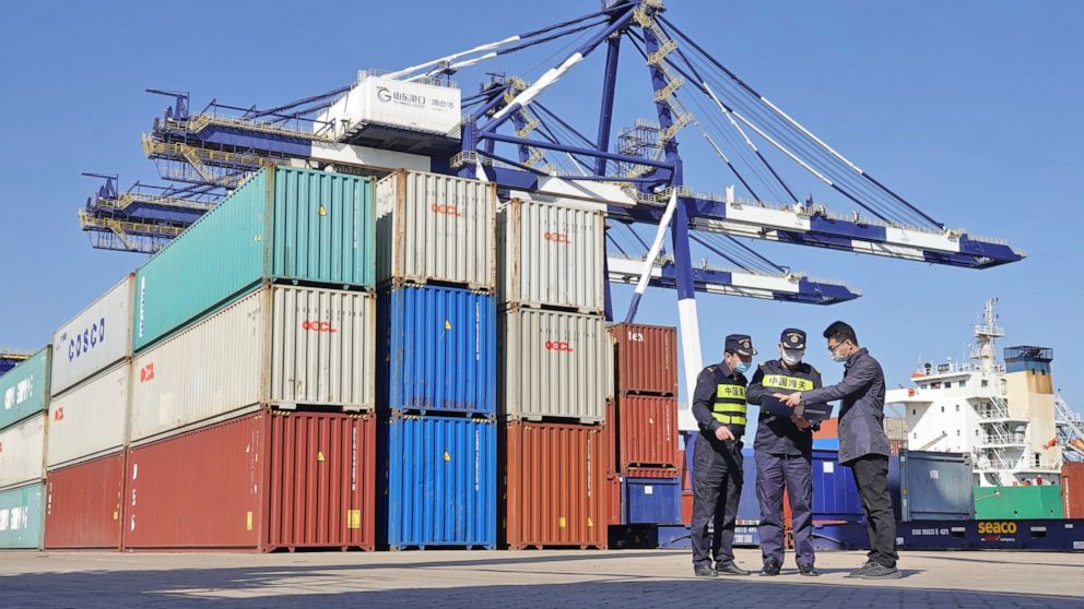 Custom officials check documents with a man at a container port in Yantai in eastern China's Shandong province Tuesday, Oct. 12, 2021. China’s import and export growth slowed in September amid shipping bottlenecks and other disruptions combined with 