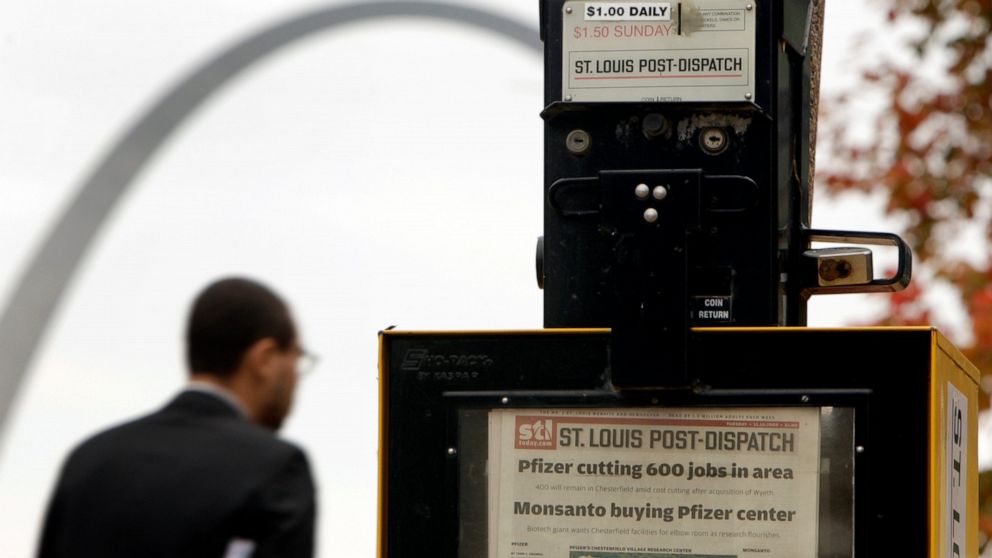 FILE - In this Nov. 10, 2009 photo, a man walks past a St. Louis Post-Dispatch newspaper box as the Gateway Arch is seen in the background in St. Louis. Lee Enterprises successfully fought off a hostile takeover earlier this year, but now the newspap