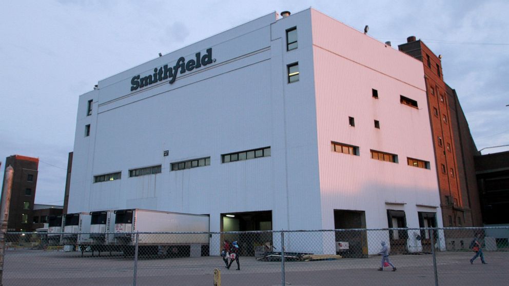 FILE - Employees of two departments at the Smithfield pork processing plant in Sioux Falls, S.D., report to work, May 4, 2020. Smithfield Foods will pay restaurants and caterers $42 million to settle a lawsuit that accused the giant meat producer of 