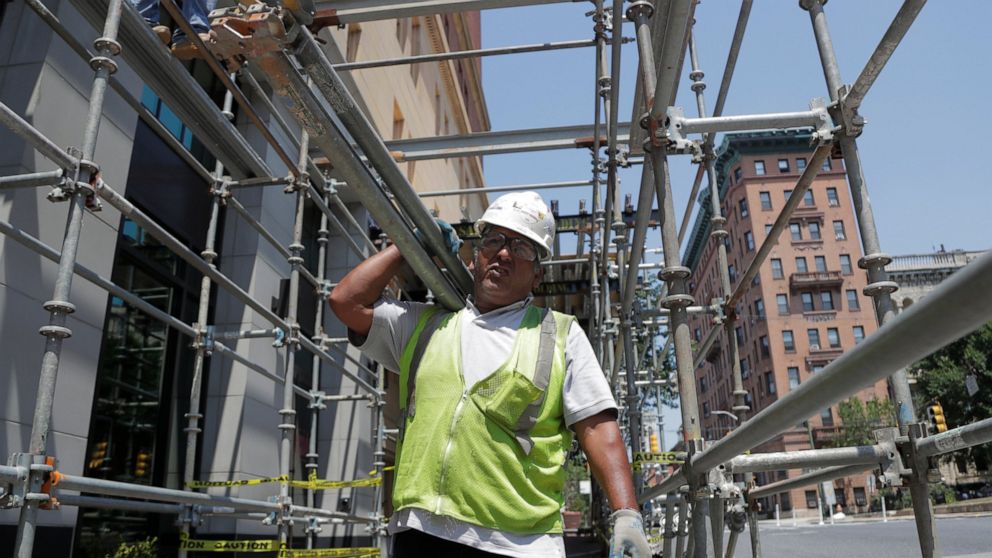 FILE - In this July 29, 2019, file photo a construction worker carries bars while helping build a scaffolding on the side of a hotel in the Mount Vernon section of Baltimore. On Thursday, Aug. 1, the Commerce Department reports on U.S. construction s