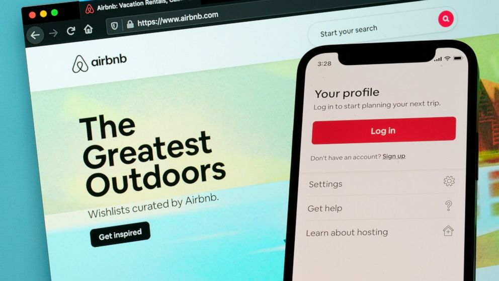 FILE - The login page for Airbnb's iPhone app is seen in front of a computer displaying Airbnb's website, Saturday, May 8, 2021, in Washington. Airbnb is getting a boost from the rebound in travel. The lodging-reservations company said Tuesday, May 3