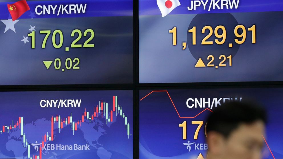 A currency trader walks near screens showing the foreign exchange rates at the foreign exchange dealing room in Seoul, South Korea, Thursday, Aug. 22, 2019. Asian stock markets are mixed Thursday following Wall Street’s rebound as investors looked ah