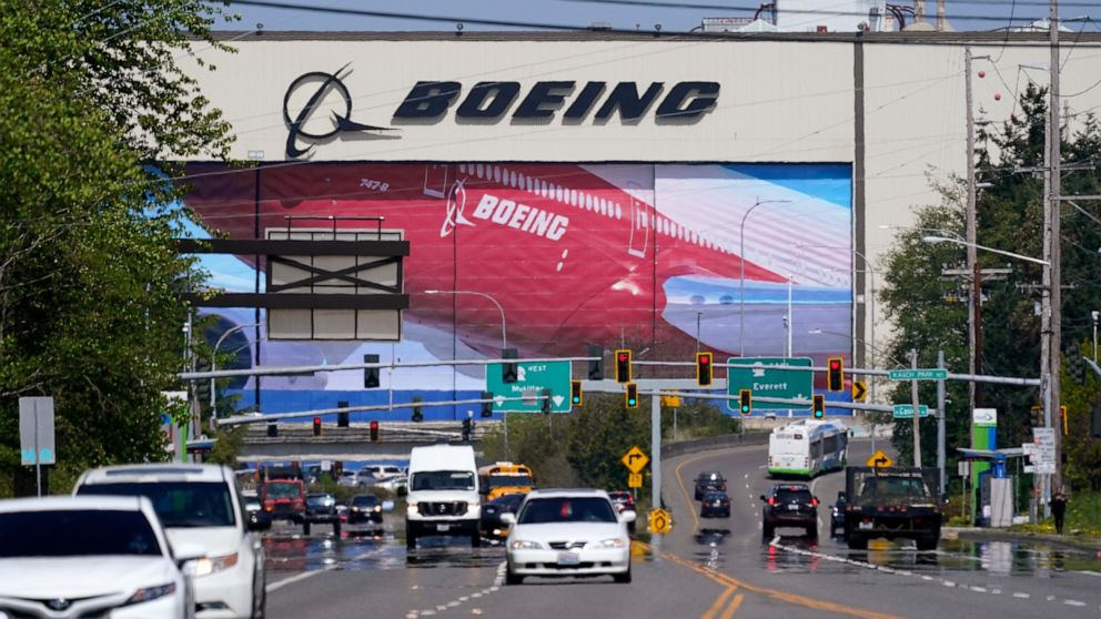 FILE - Traffic drives in view of a massive Boeing Co. production plant, where images of jets decorate the hangar doors, Friday, April 23, 2021, in Everett, Wash. Boeing says global geopolitical concerns are a big reason why it is dropping more than 1