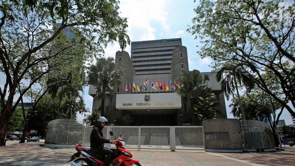 FILE - In this June 6, 2018, file photo, a motorcyclist rides past the Bank Negara Malaysia in Kuala Lumpur, Malaysia. The country's central bank on Tuesday, May 7, 2019, cut interest rates for the first time in nearly three years to help support gro
