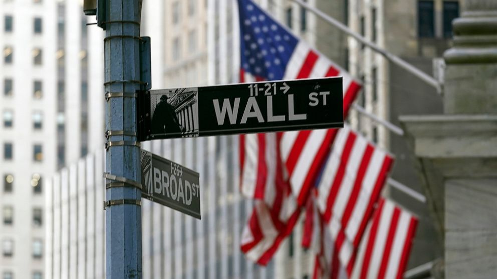 FILE - The Wall St. street sign is framed by the American flags flying outside the New York Stock exchange, on Jan. 14, 2022, in the Financial District. Stocks are opening lower on Wall Street on Tuesday, May 31, 2022, and crude oil prices rose sharp