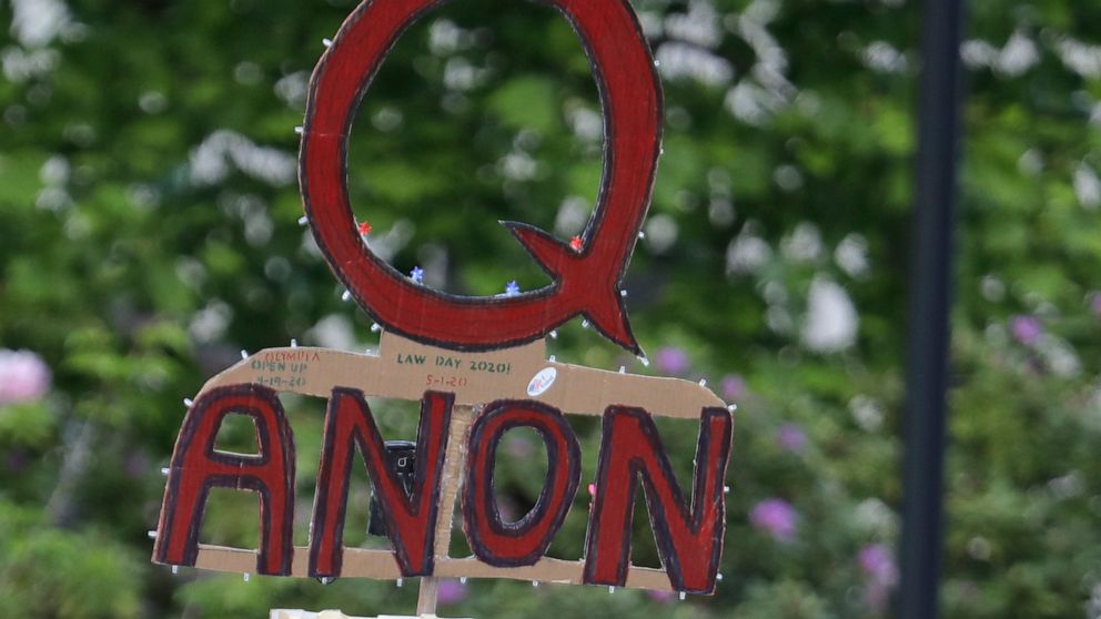 FILE - In this May 14, 2020, file photo, a person carries a sign supporting QAnon during a protest rally in Olympia, Wash, USA. The social media company Twitter said Tuesday Jan. 12, 2021, it has suspended more than 70,000 accounts associated with th